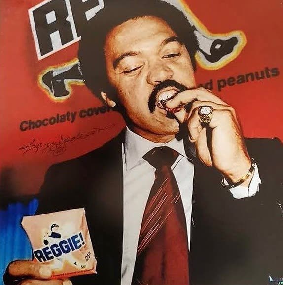 The original 1978 REGGIE! Bar promotional poster: a young Reggie Jackson in a suit taking a bite of the bar, signed across the artwork
