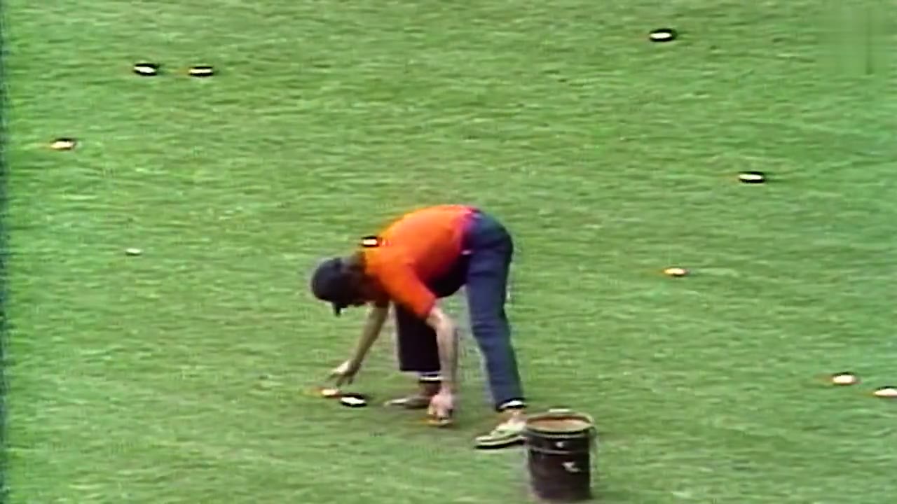 The Yankee Stadium outfield in 1978, its grass dotted with dozens of discarded orange REGGIE! Bar wrappers as a grounds crew member collects them