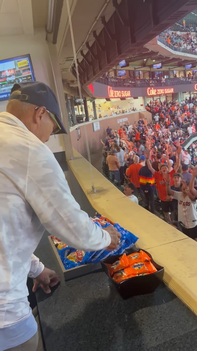 A tray of REGGIE! Bars being handed down toward a cheering crowd of fans at a ballpark