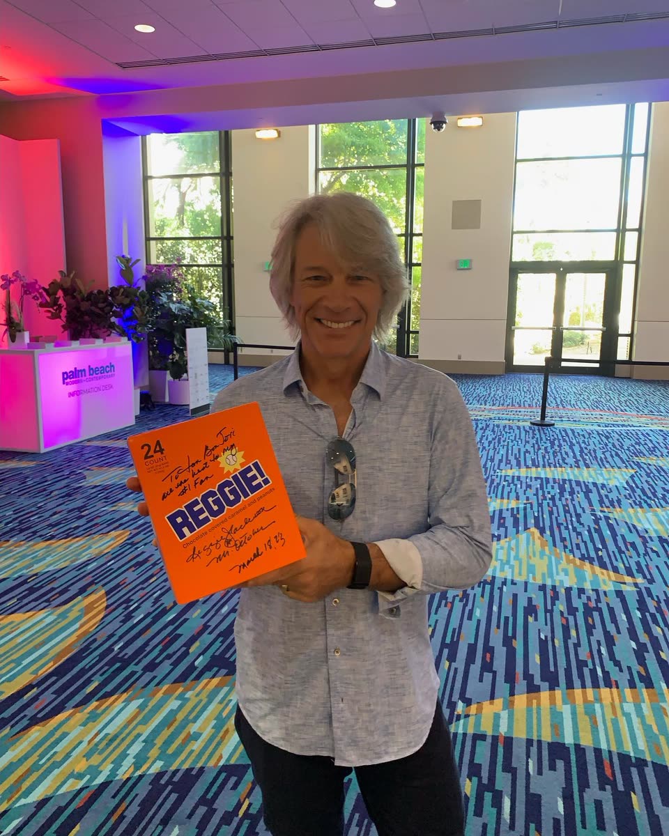 A fan holding up a 24-count REGGIE! box signed and inscribed by Reggie Jackson